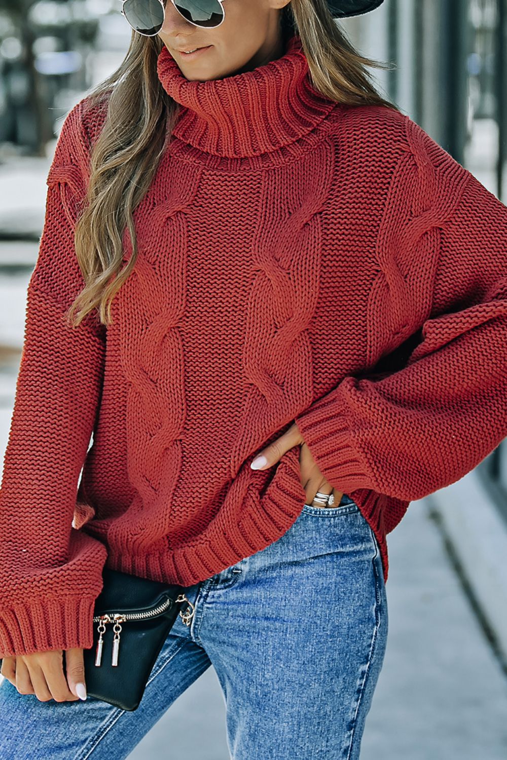 Rust cable knit turtleneck sweater with relaxed fit and ribbed cuffs.