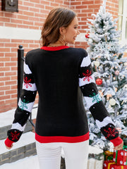 Black acrylic sweater with red neckline and cuffs, featuring snowflake and wave pattern on sleeves.
