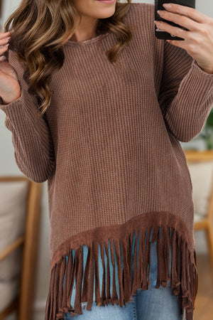 Brown waffle knit top with suede fringe hem and long sleeves.