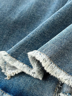 Denim maxi dress detail showing frayed hem and cotton fabric.