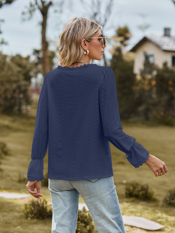 Navy textured blouse with lace trim neckline and flared cuffs.