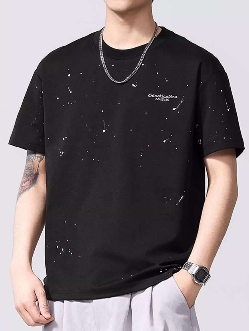 Black cotton t-shirt with artistic paint splatter pattern and embroidered text detail.