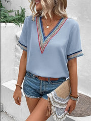 Light blue v-neck top with colorful embroidered trim on neckline and sleeves.