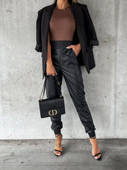 Black leatherette gathered waist joggers with elastic cuffs and pockets.