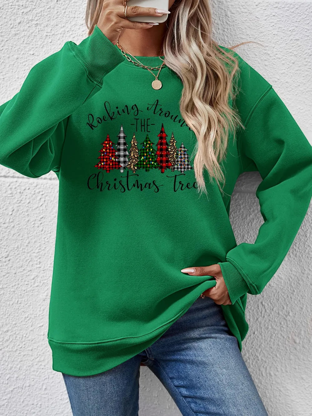 Green crewneck sweatshirt with graphic Christmas trees and text.