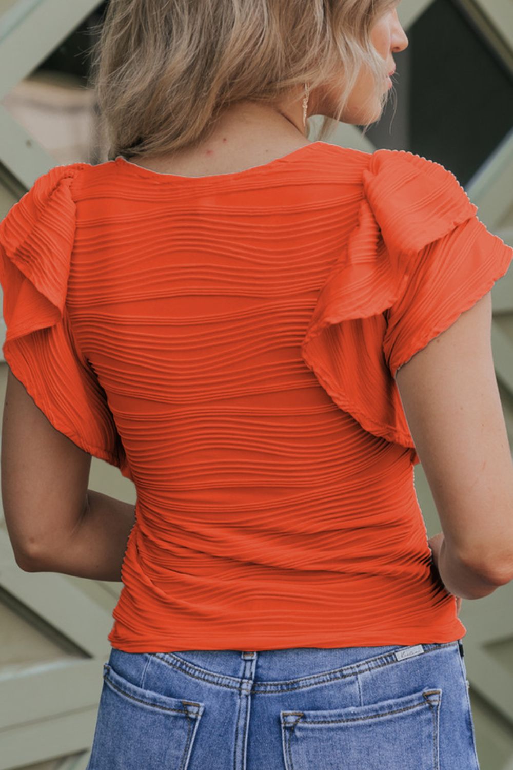 Orange textured bodysuit with ruffled short sleeves and ruched sides.