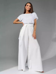 White sequin top jumpsuit with wide-leg pants and a tie waist.