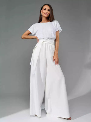 White sequin top jumpsuit with wide-leg pants and a tie waist.