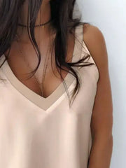 Apricot silky cami top with deep plunge neckline and layered necklaces.