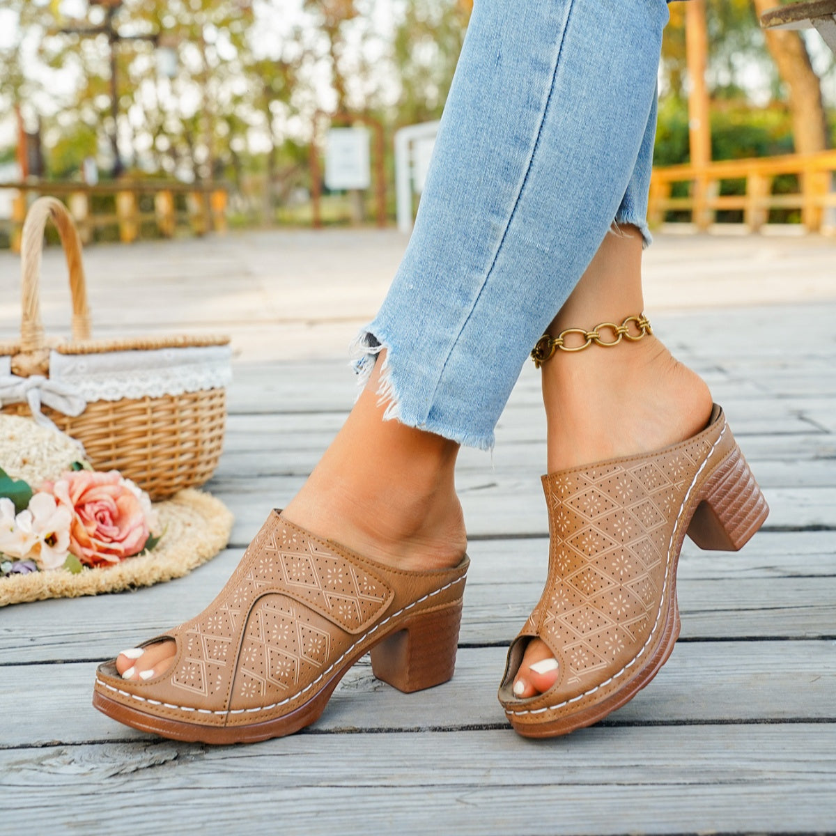 Tan peep-toe block heel mules with cut-out diamond pattern and white stitching.