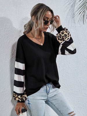 Black waffle knit top with colorblock sleeves featuring leopard print, stripes, and geometric patterns.