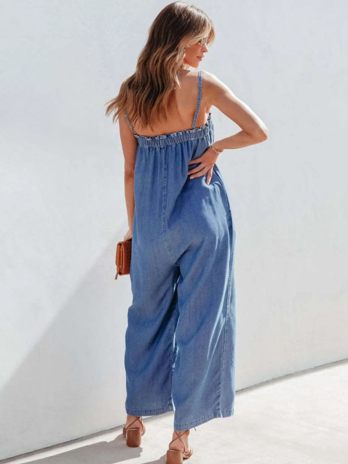 Medium denim jumpsuit with gathered bodice and wide legs.