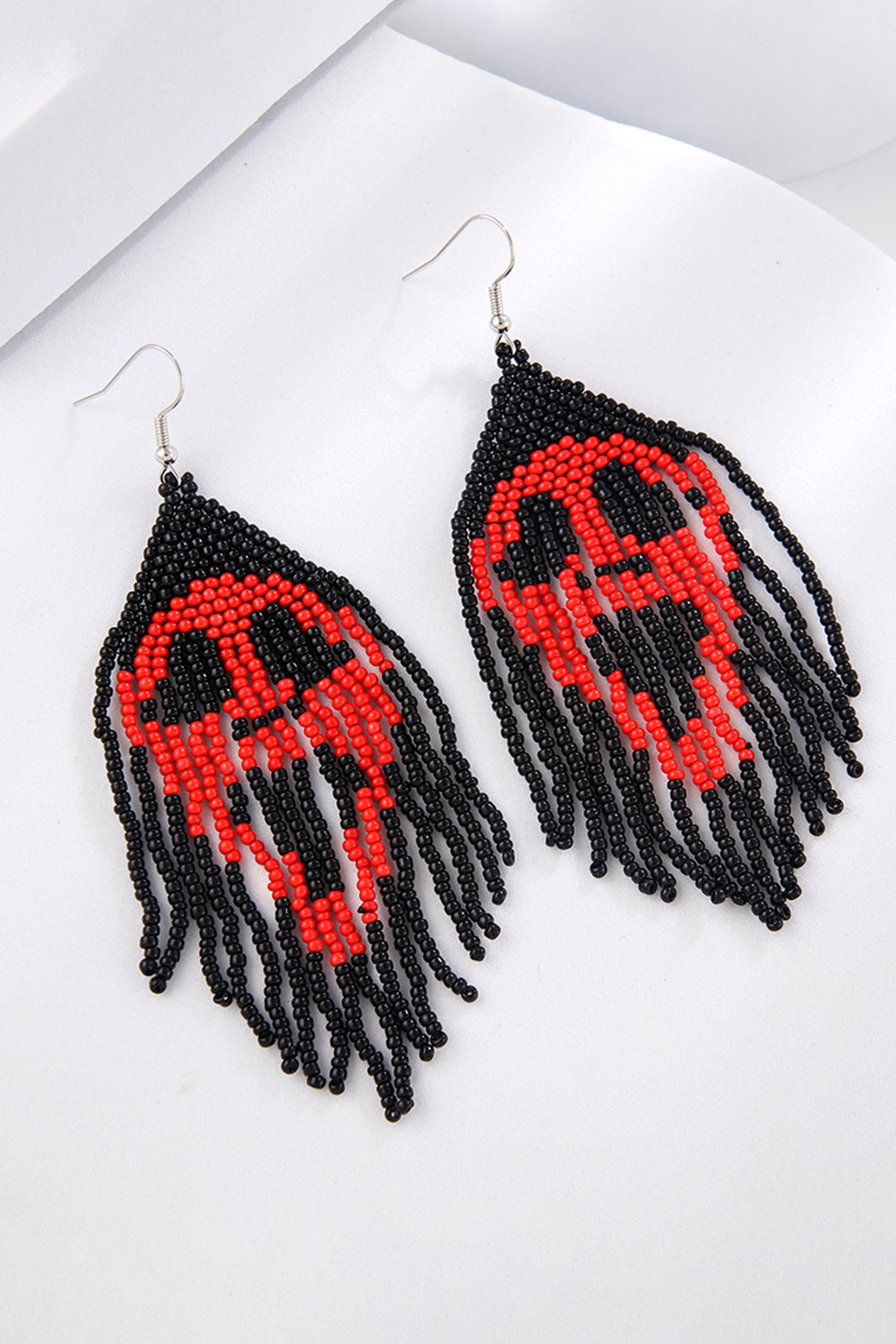 Beaded skull fringe earrings in red and black, featuring dangling strands.