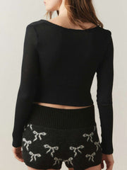 Black ribbed crop top with distressed neckline and long sleeves.
