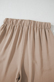 Camel drawstring palazzo pants with elastic waistband and textured fabric.