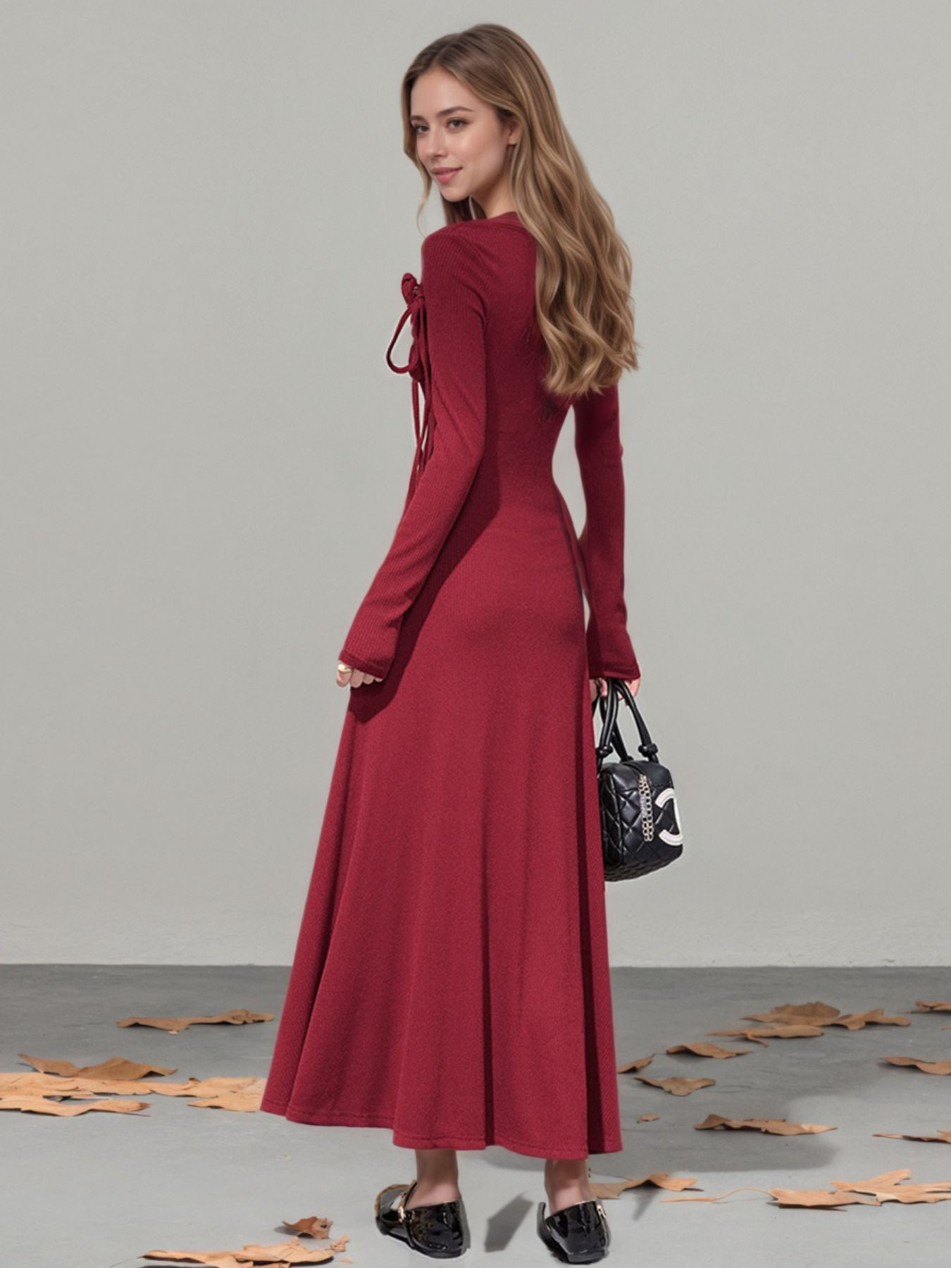 Burgundy long-sleeve maxi dress with asymmetrical neckline and tie detail.