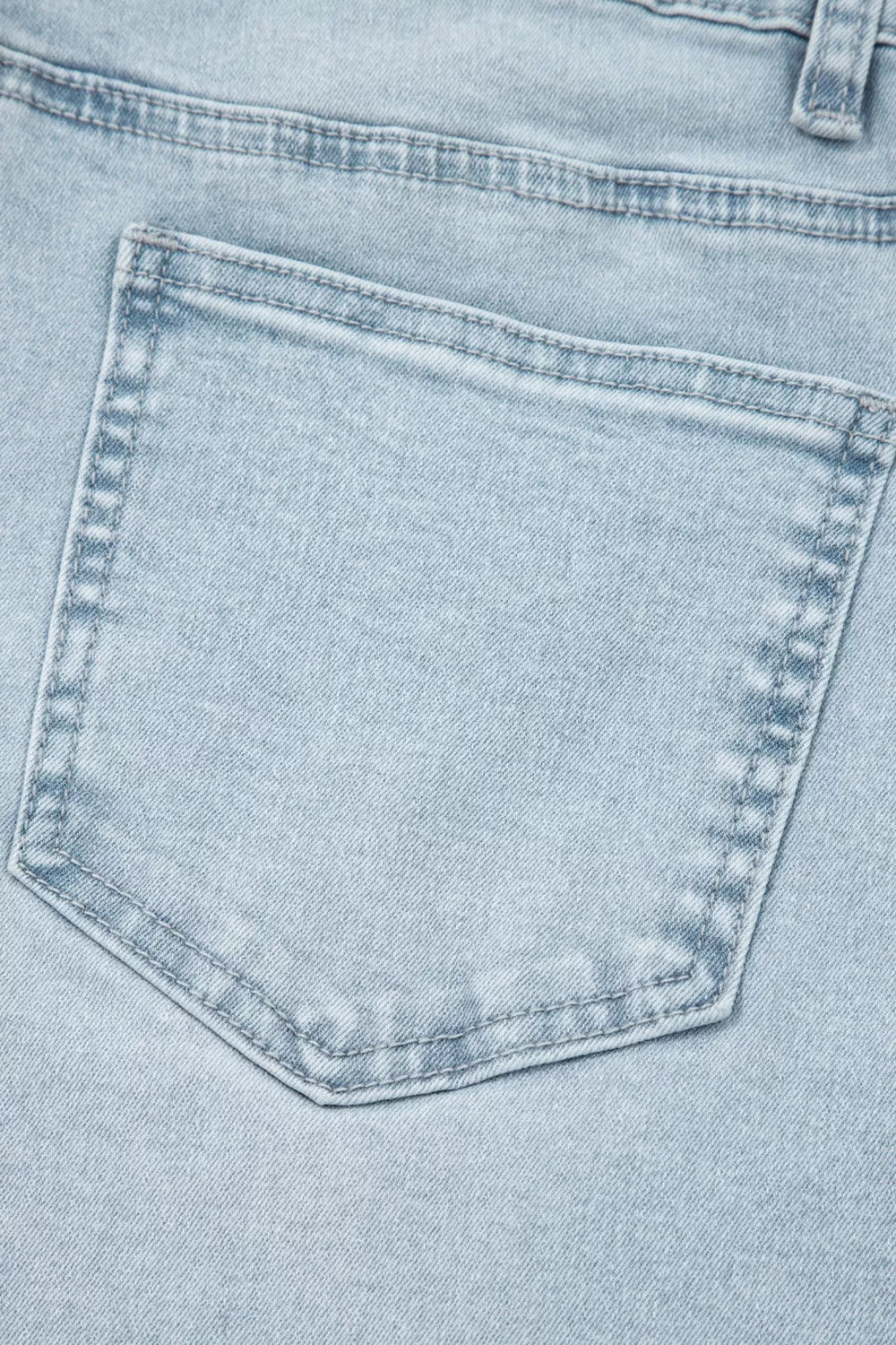 Light wash denim jeans back pocket detail with contrast stitching.