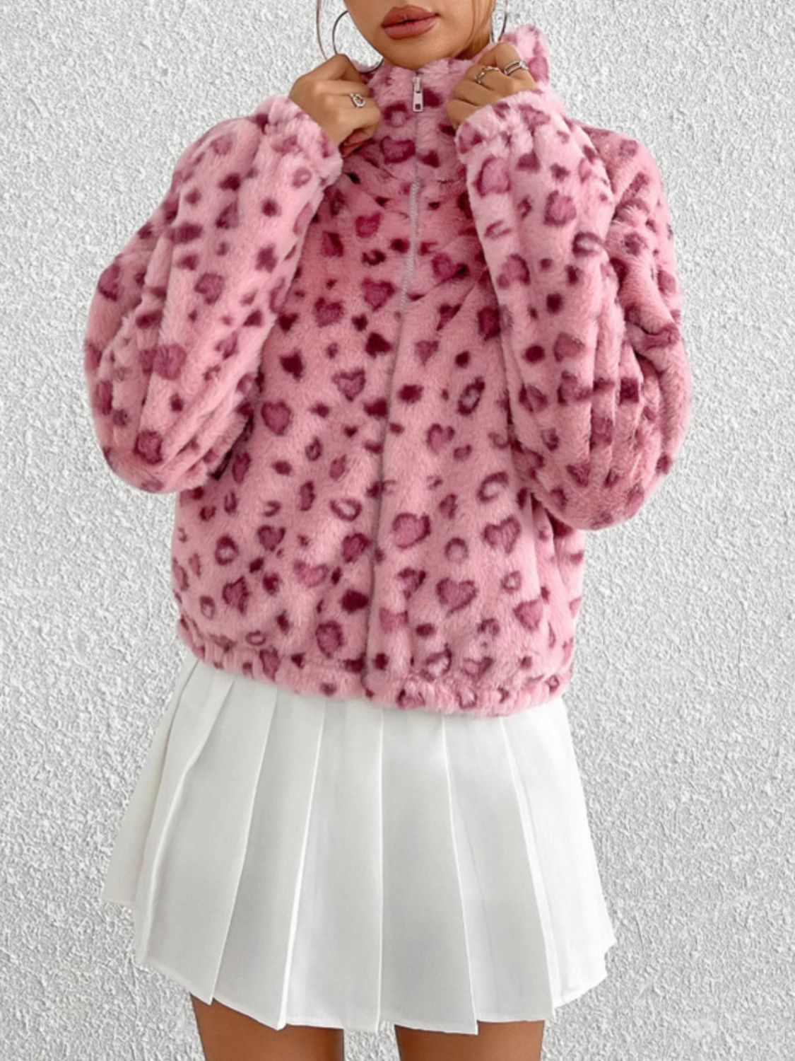 Blush pink faux fur zip track jacket with heart pattern, high neck, and long sleeves.