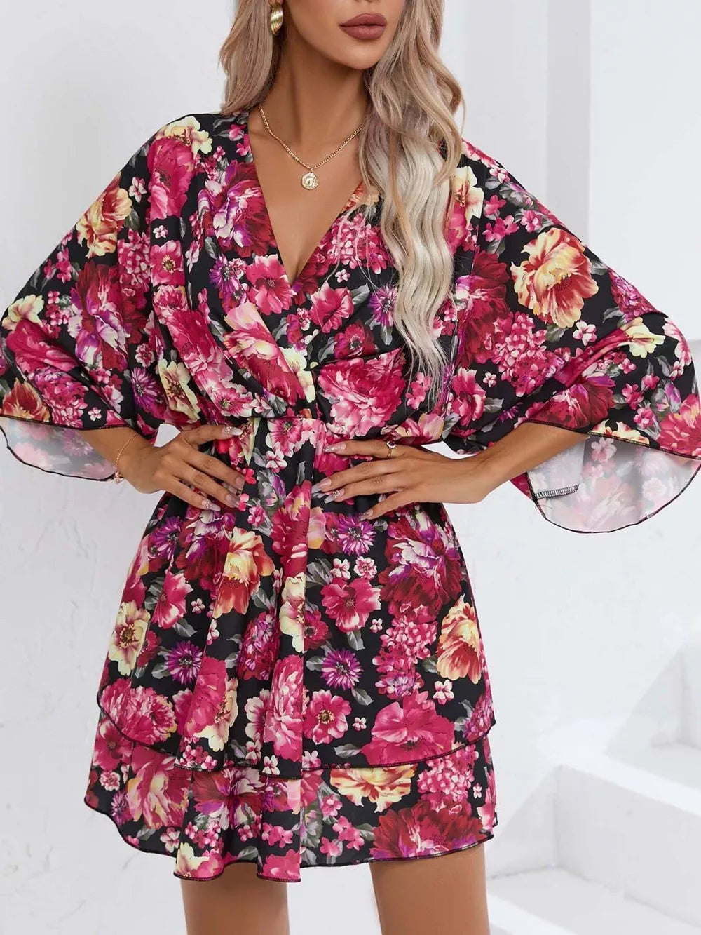 Floral ruffle hem mini dress in black with pink and yellow flowers, V-neck, and flutter sleeves.