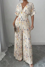 Floral pleated wide-leg jumpsuit with a cinched waist and V-neck.