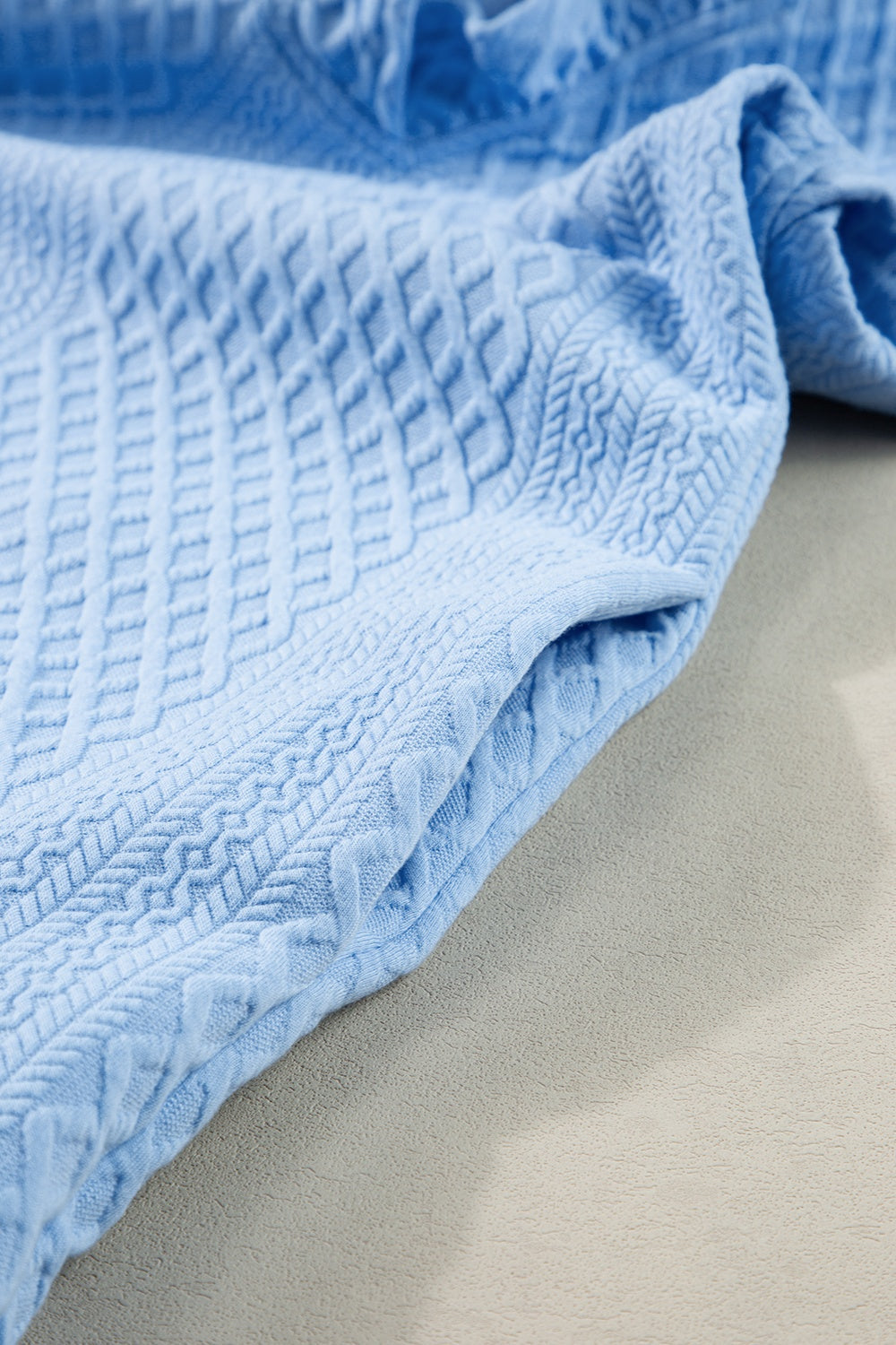 Light blue textured trapeze dress with ruffle sleeves and diamond pattern detail.