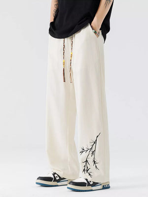Beige wide-leg sweatpants with embroidered branch detail and beaded drawstring.