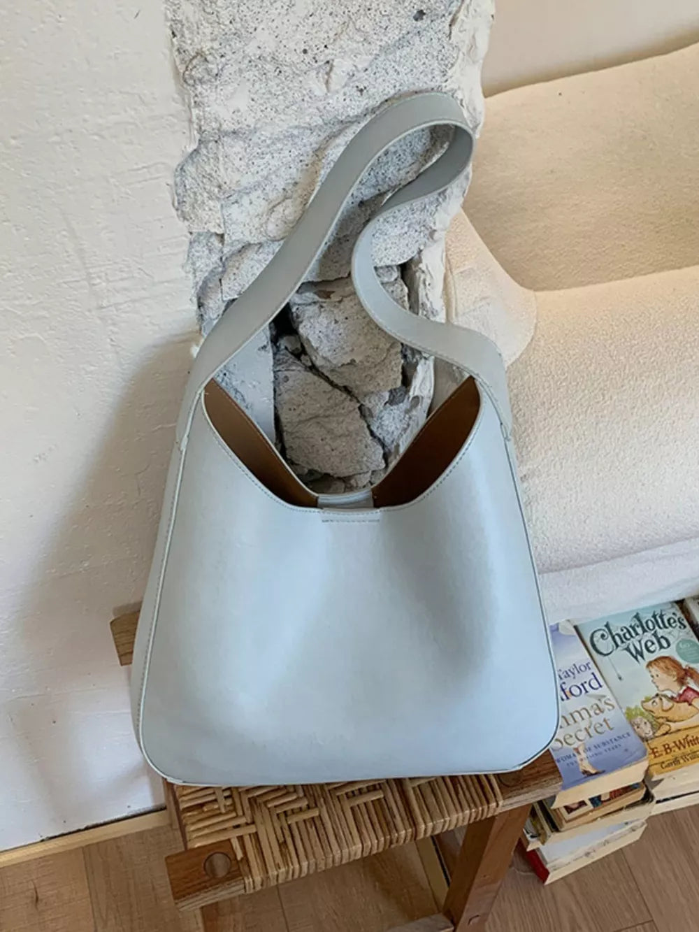 Sleek light blue PU leather shoulder bag with curved strap and open top.