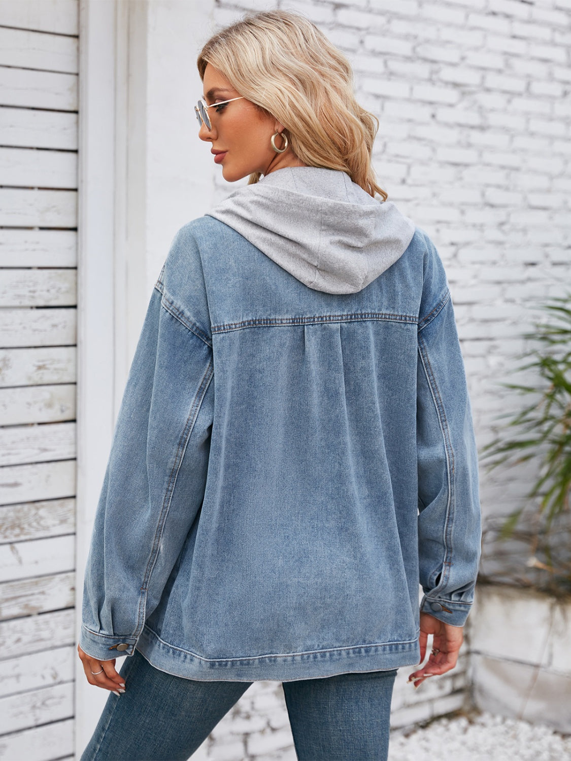 Oversized denim jacket with grey hood detail, buttoned cuffs, and classic blue wash.
