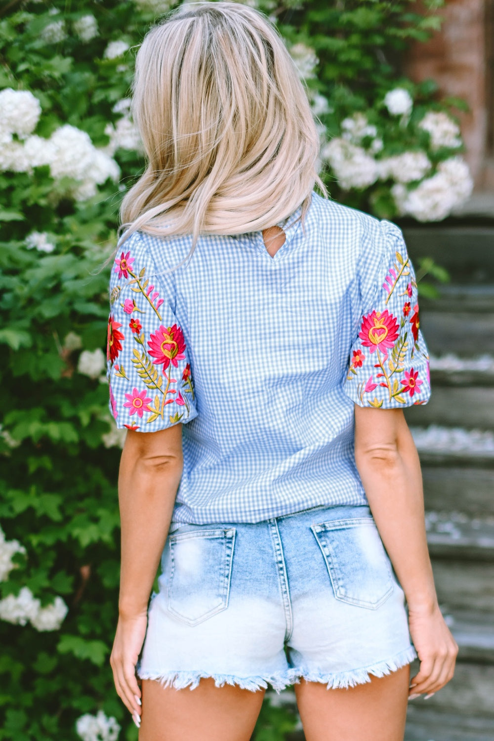Light blue gingham blouse with embroidered floral sleeves and a keyhole back.
