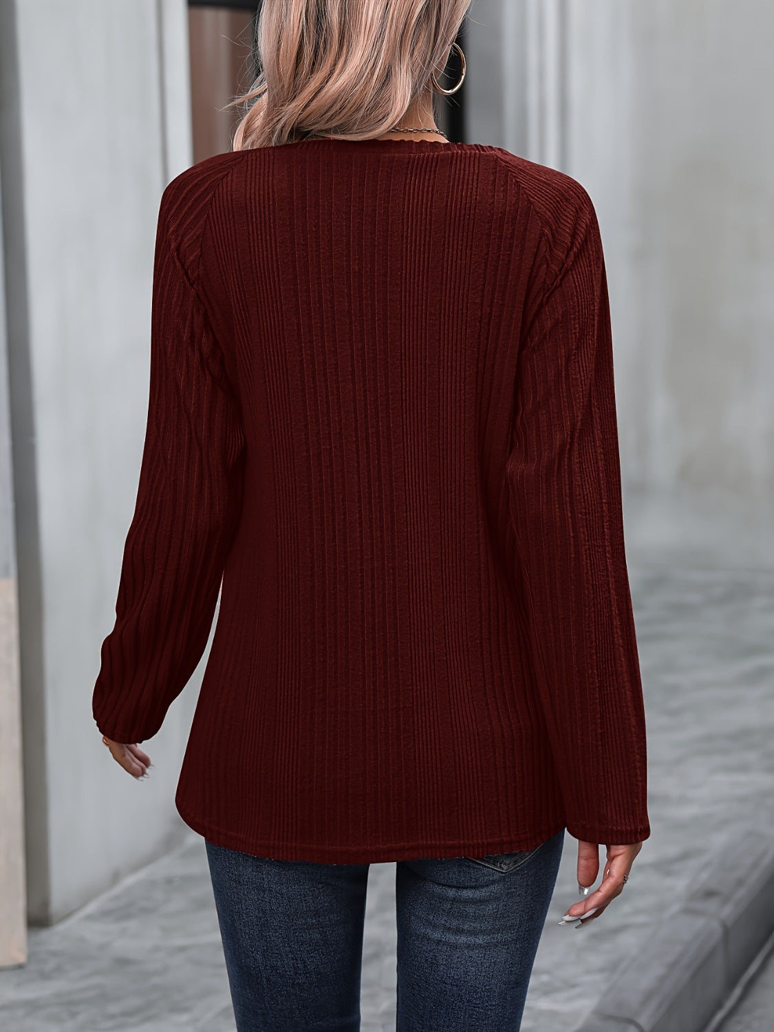 Burgundy ribbed knit raglan sweater with button trim detail.
