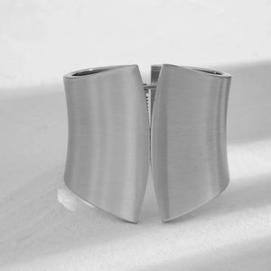 Sculptural silver-toned cuff bracelet with a brushed finish and curved panels.
