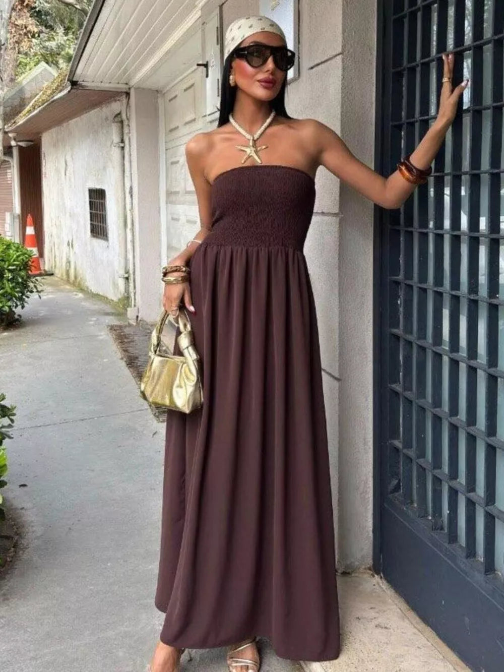 Dark brown strapless relaxed maxi dress with smocked bodice and flowing skirt.