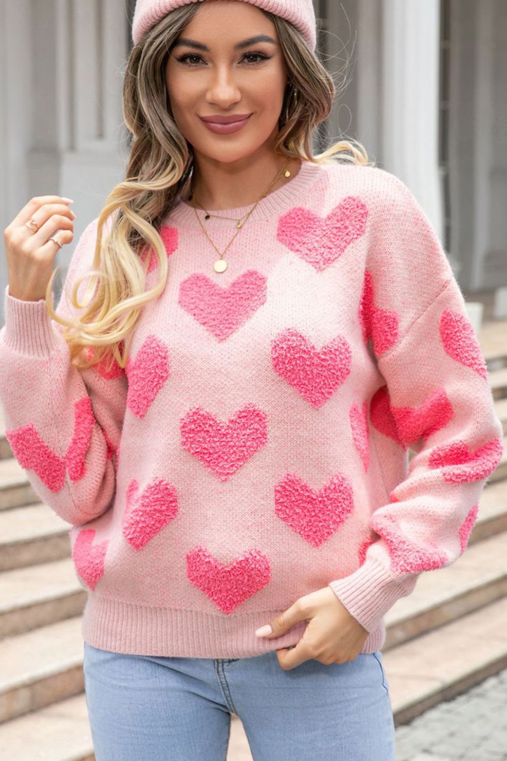Blush pink knit sweater with textured heart pattern, crew neck, and long sleeves.