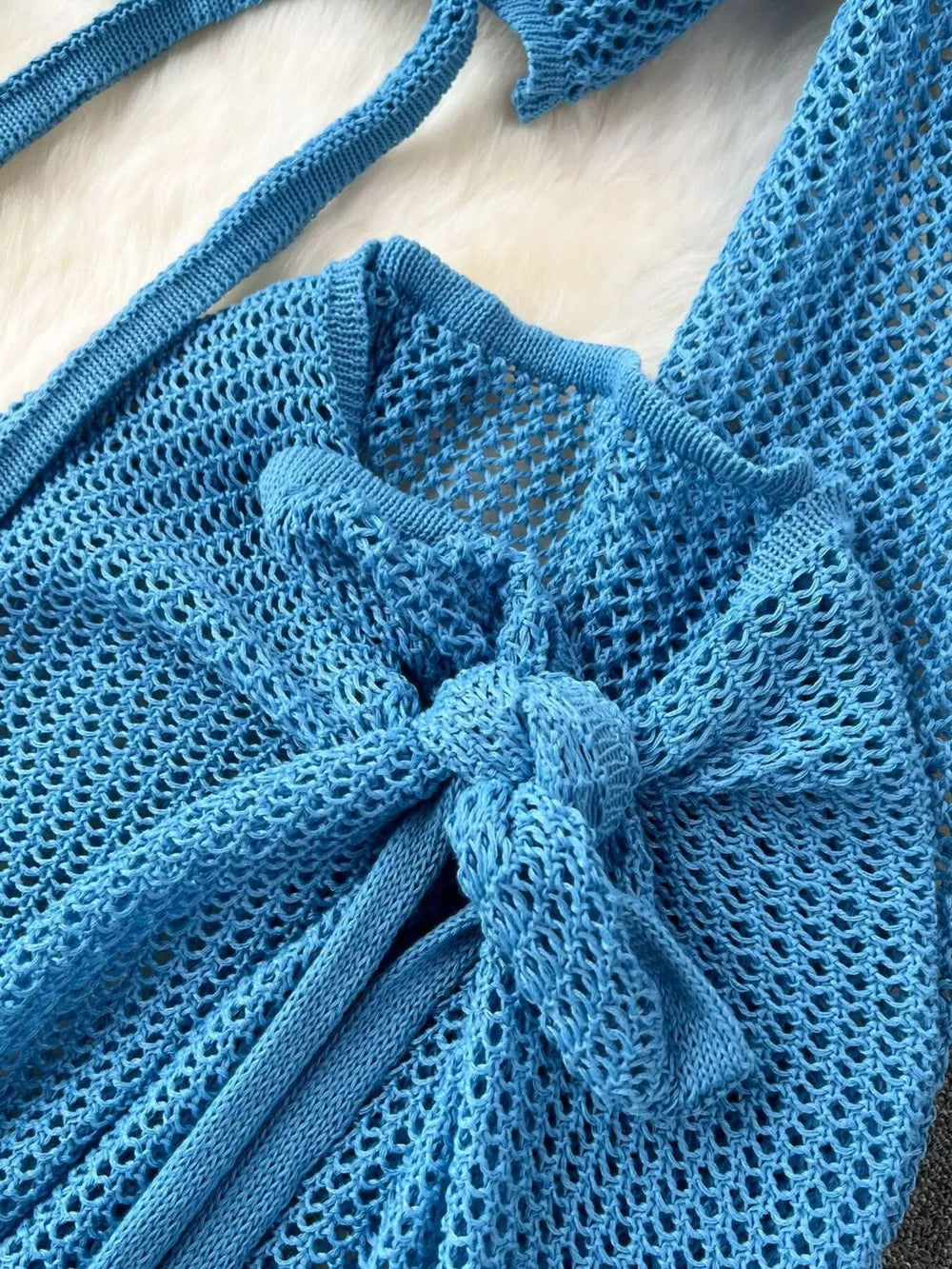 Blue knit tied crop top with open weave detail and tie closure.