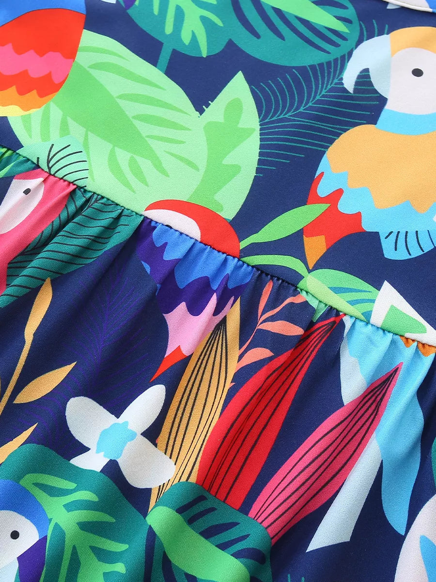 Navy blue baby dress with vibrant parrot and tropical leaf print, cotton blend fabric.