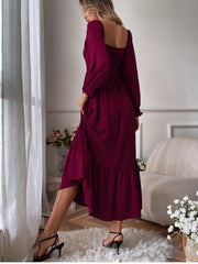 Burgundy midi dress with smocked bodice, puff sleeves, and ruffled hem.
