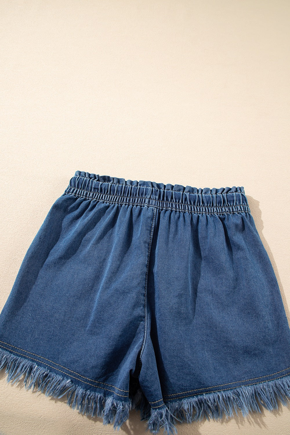 Navy denim drawstring shorts with frayed hem and elastic waistband.
