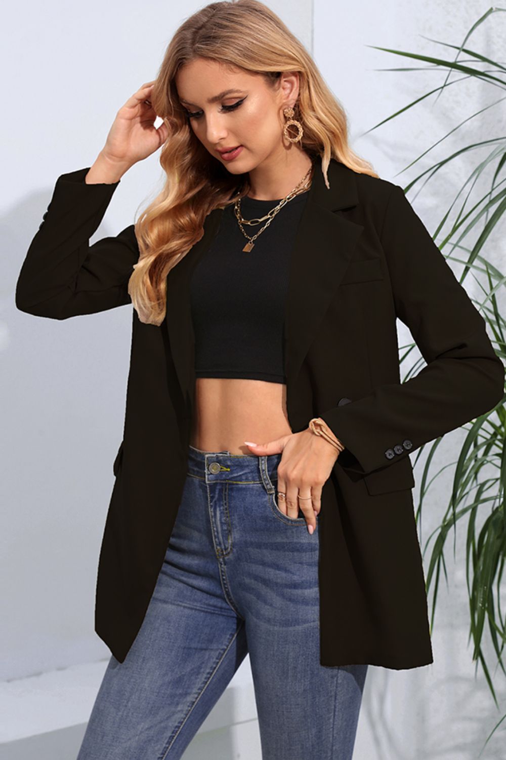 Black double-breasted blazer with flap pockets and buttoned cuffs, styled with jeans.