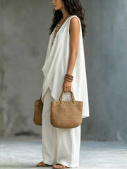 White asymmetrical sleeveless top and wide-leg pants set with a draped neckline.