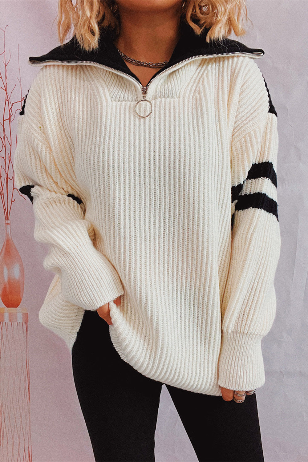White ribbed knit quarter-zip sweater with black stripe sleeves and collar.