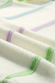 Ivory knit henley sweater with pastel stripes in purple, blue, and green.