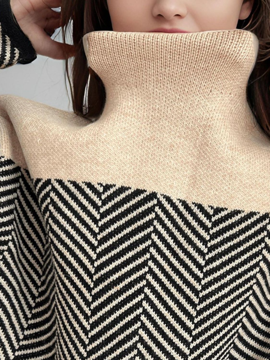 Chevron knit turtleneck sweater in tan with black chevron pattern and ribbed collar.