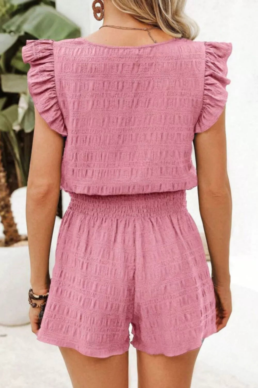 Pink textured two-piece set with ruffled cap sleeves and smocked waist shorts.