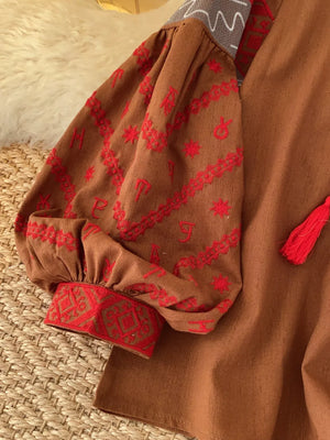 Brown folk-inspired shirt with red embroidered puff sleeves, cuffs, and tassel detail.