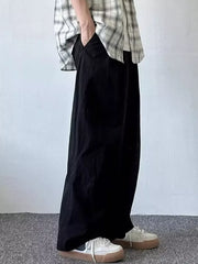 Relaxed fit black sweatpants with pockets, worn by a man with hands in pockets.