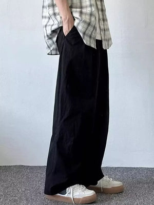 Relaxed fit black sweatpants with pockets, worn by a man with hands in pockets.