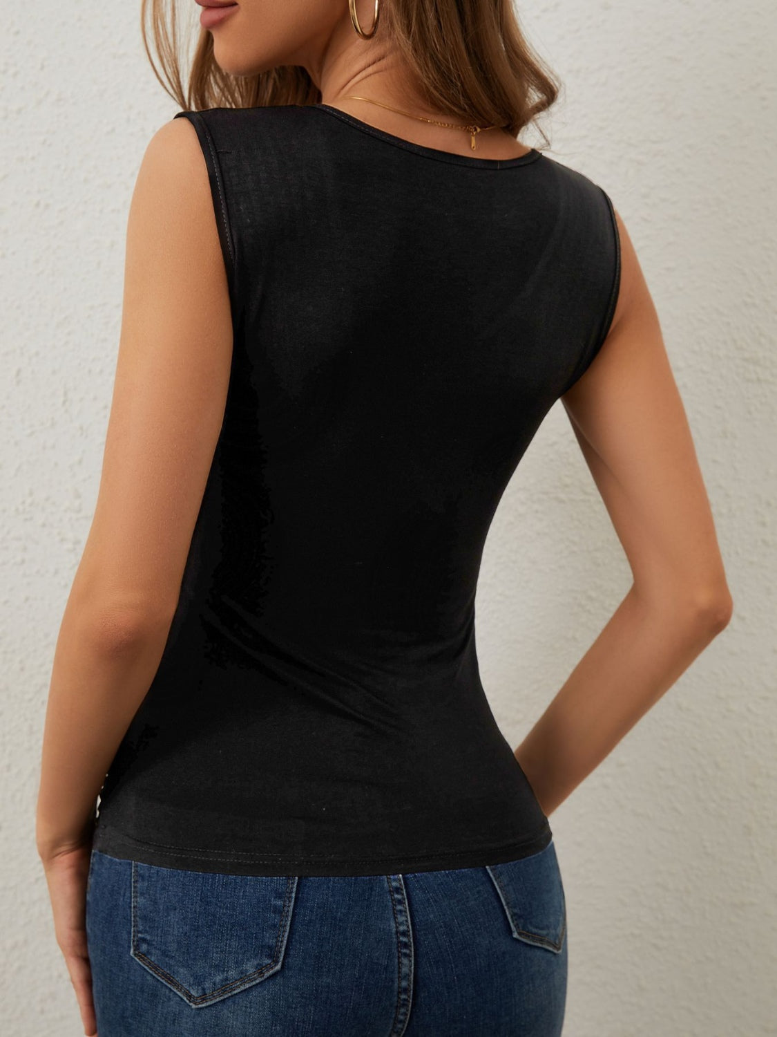 Black tank top with shoulder embellishments and a scoop neckline.