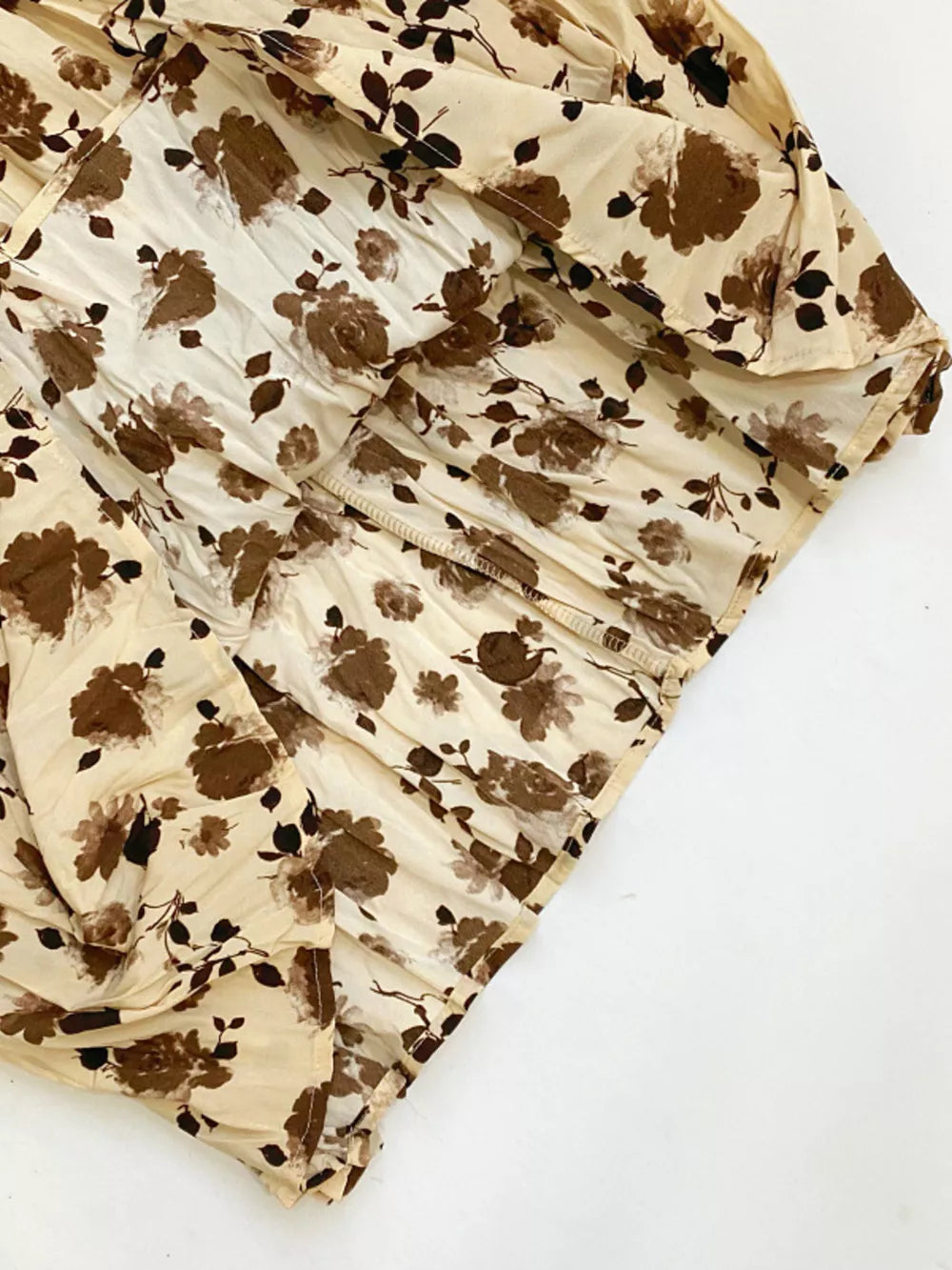 Botanical pleated midi skirt in tan with a brown floral print and crinkled texture.