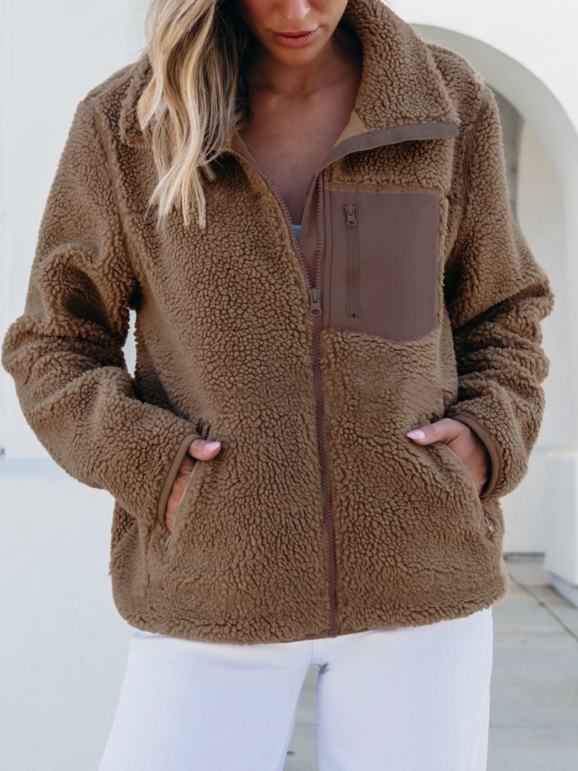 Brown sherpa zip-up jacket with contrast patch pocket and zipper details.