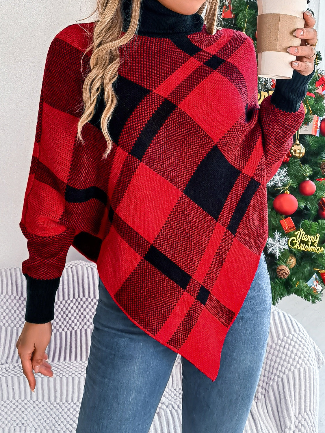 Red and black tartan turtleneck poncho sweater with asymmetric hem and cuffed sleeves.